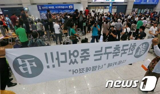 본문 이미지 - 2014 브라질 월드컵에서 H조 최하위를 기록하며 16강 진출에 실패한 축구대표팀 홍명보 감독과 선수들이 30일 오전 인천국제공항을 통해 귀국한 가운데 일부 팬들이 홍 감독의 언론 인터뷰 도중 &#39;한국 축구는 죽었다!&#39;고 적힌 현수막을 들고 있다.한국 축구의 9번째 월드컵 도전은 16년 만의 무승이라는 최악의 성적으로 막을 내렸다. 2014.6.30/뉴스1 © News1 오대일 기자
