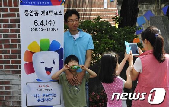 본문 이미지 - 6·4지방선거일인 4일 광주 서구 풍암동 4투표소에는 투표를 마친 한가족이 투표소 앞에서 인증샷을 찍고 있다.2014.6.4/뉴스1 © News1   김태성 기자