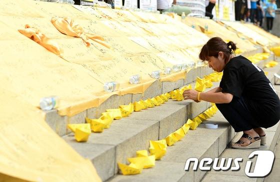 본문 이미지 - 세월호 가족대책위가 13일 오전 여의도 국회 본청 앞에서 가진 4.16참사 특별법 관련 가족대책위 입장발표 기자회견에서 한 참가자가 노란 종이배를 놓고 있다.세월호 가족대책위는 진실규명을 위한 4.16특별법 제정 촉구와 진실규명을 촉구했다. 2014.7.13/뉴스1 © News1   박세연 기자