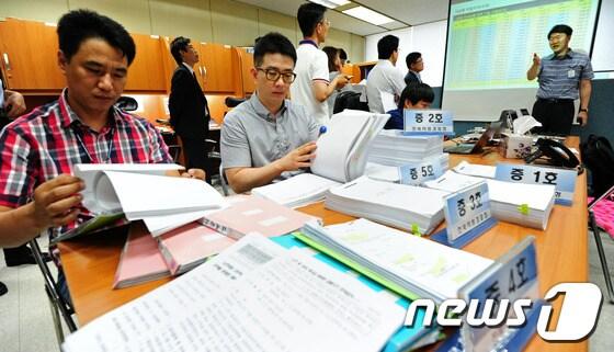 본문 이미지 - 노인을 대상으로 고수익 보장 명목으로 210억원대 금융 사기 조직을 운영한 피의자 검거 브리핑이 열린 15일 오전 전북지방경찰청 기자실에서 관련 경찰관들이 브리핑에 앞서 압수 자료를 정리하고 있다. 2014.7.15/뉴스1 © News1 김대웅 기자