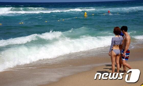 본문 이미지 - 27일 강원 강릉시 경포해변을 찾은 연인이 너울성 파도로 입수가 금지되어 바다에 들어가지 못하고 있다. 이날 강원 동해안 대부분의 해수욕장은 너울성 파도로 입수가 금지됐다.이날 오전11시 기상청에서는 오후 해상 예보로 풍속 8~12m/s, 파고 1~2m가 일 것으로 발표했다. 2014.7.27/뉴스1