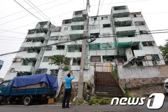 본문 이미지 - 철거를 앞둔 서울 서대문구 냉천동 금화아파트 앞에서 3일 오후 한 시민이 아파트를 휴대전화 카메라로 촬영하고 있다. 1971년에 준공된 금화아파트는 지난 2007년 7월 안전진단 결과 붕괴 가능성이 높은 최하위 E급 판정을 받았다. 2014.7.3/뉴스1 ⓒ News1