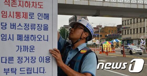 본문 이미지 - 지난 5일 석촌지하차도 앞에서 발생한 싱크홀의 안전 점검을 위해 13일 오후 4시부터 6시까지 백제고분로 석촌역~배명고사거리 지하차도가 전면 통제되고 있다. 한 공사 관계자가 점검으로 버스 정류장 임시 폐쇄를 알리는 공고문을 붙이고 있다. ⓒ News1 송은석 기자