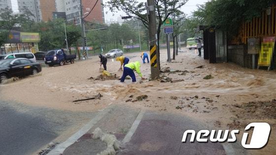 본문 이미지 - 18일 울산 중구 태화동의 유곡중학교 옆 등산로에서 흙탕물이 흘러내려 주변 도로가 침수됐다. 중구청 직원들이 배수로를 막은 토사를 치우고 있다. ⓒ News1 조창훈 기자