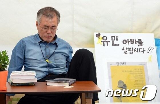 본문 이미지 - 2014년 8월 당시 새정치민주연합 의원이던 문재인 대통령이 서울 광화문광장에서 단식 농성을 하는 모습. 탁자 위 휴대폰 아래 놓인 책이 '비통한 자들을 위한 정치학'이다. 2014.8.24/뉴스1 ⓒ News1 DB