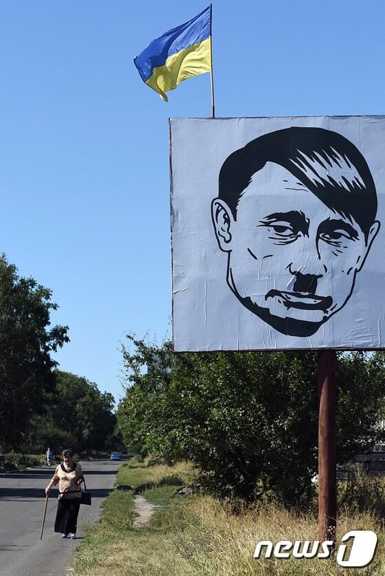 본문 이미지 - 우크라이나 도네츠크 인근의 한 마을에 히틀러와 비슷하게 묘사한 푸틴 대통령의 그림이 걸려 있다.ⓒ AFP=뉴스1