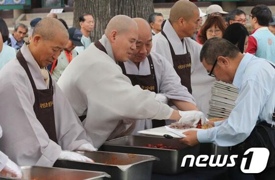 본문 이미지 -  서울 종로구 조계사 대웅전 앞마당에서 열린 "빈곤문제 해소를 위한 2014년 시민초청 무차대회"에서 자승 총무원장을 비롯한 스님들이 시민들에게 저녁 공양 배식을 하고 있다. ⓒ News1 송원영 기자
