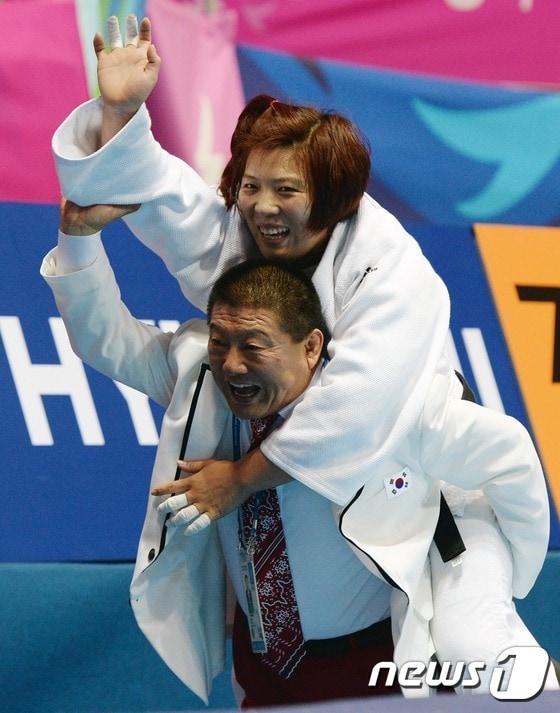 본문 이미지 - 한국 유도 대표팀의 정경미가 22일 오후 인천 도원체육관에서 열린 "2014 아시안게임" 여자 유도 78kg급 결승전 북한의 설경과의 경기에서 금메달을 획득 후 서정복 감독 등에 업혀 기뻐하고 있다.  ⓒ News1 손형주 기자