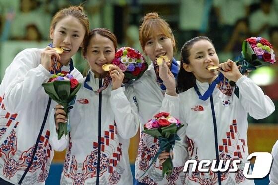 본문 이미지 - 남현희, 오하나, 전희숙, 김미나가 24일 오후 경기 고양시 일산서구 대회동 고양실내체육관에서 열린 2014 인천아시아경기대회 펜싱 여자 플뢰레 단체 결승전에서 우승한 뒤 수상대에 올라 금메달을 깨물고 있다. 2014.9.24/뉴스1 ⓒ News1 정회성 기자