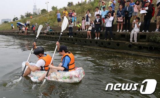 본문 이미지 - 제과업계의 과자 과대포장에 항의하는 대학생들이 28일 오후 서울 잠실한강공원 선착장에서 과자 150개를 이어 붙여 만든 '과자 뗏목'을 타고 힘차게 노를 젓고 있다. 2014.9.28/뉴스1 ⓒ News1 오대일 기자