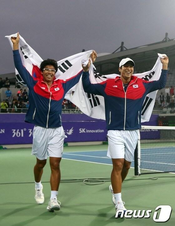 본문 이미지 - 29일 인천 열우물 테니스경기장에서 열린 2014 인천아시안게임 테니스 남자복식 결승에 출전한 임용규-정현 조가 인도의 사케즈 미네니-사남 싱 조에 승리해 금메달을 확정짓고 태극기를 두르고 코트를 돌고 있다. 2014.9.29/뉴스1 2014.09.29/뉴스1 ⓒ News1 한재호 기자