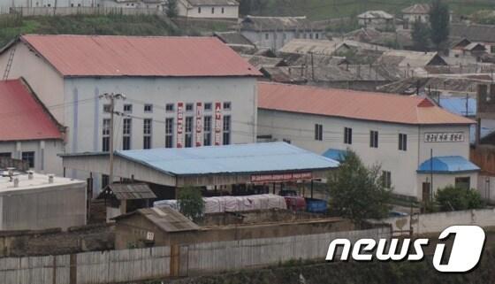 본문 이미지 - 북-중 접경지에서 바라본 북한의 모습. 무채색 속 사이사이 보이는 사상문구와 북한 주민 및 국경 경비대, 뙈기밭의 모습에서 북한 주민의 현재 삶을 엿볼 수 있다. ⓒ News1