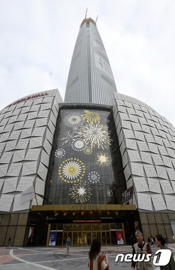 본문 이미지 - 지난 15일 서울 송파구 롯데면세점 월드타워점 앞에서 중국인 관광객들이 기념촬영을 하고 있다. 관세청은 지난 14일 서울 시내면세점 특허 심사 결과 호텔롯데 소공점, 신세계디에프의 신세계백화점 충무로 본점, 두산의 동대문 두산타워가 사업자로 선정됐다고 발표했다. 이번에 롯데는 소공동 본점 수성에는 성공했지만 지난해 매출 약 5000억원으로 단일 매장 기준 국내 3위의 월드타워점을 놓치게 됐다. 2015.11.15/뉴스1 ⓒ News1 안은나 기자