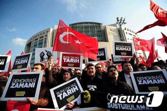 본문 이미지 - 반정부 터키 지도자 폐툴라 귤렌을 지지하는 터키 언론사 기자들이 '자유언론은 침묵하지 않는다'는 피켓을 들고 반정부 언론을 탄압하는 정부에 맞서 시위를 벌이고 있다. ⓒ AFP=뉴스1