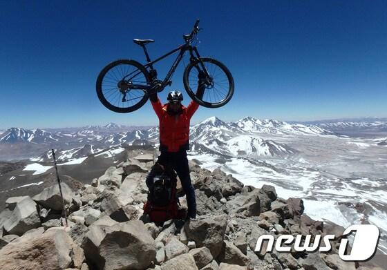 본문 이미지 - 안치영 대장이 세계 최고봉 화산인 오호스 델 살라도 등정에 성공한 후 자전거를 들고 기념촬영을 하는 모습. 사진 제공 / 미디언스 ⓒ News1