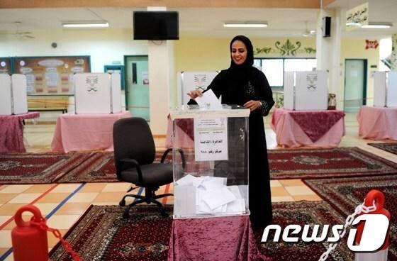 본문 이미지 - 지난 12일(현지시간) 치러진 사우디아라비아 지방선거 도중 남부 항구도시 제다에서 한 여성이 투표용지를 투표함에 넣고 있다.ⓒ AFP=뉴스1