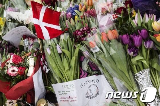 본문 이미지 - 총격 사건이 일어난 덴마크 코펜하겐 유대교 회당 인근에 놓인 덴마크 국기와 꽃다발들.ⓒ AFP=뉴스1