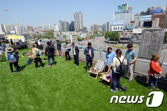 본문 이미지 - 10일 오후 시민개방행사가 진행된 서울 중구 봉래동 서울역고가를 찾은 시민들이 차량통행이 제한된 고가 위를 거닐고 있다. 서울시가 공원화 사업을 추진하고 있는 서울역고가에는 이날 총면적 2,400㎡ 규모의 인조잔디밭과 다양한 체험부스가 마련됐다. 2015.5.10/뉴스1 ⓒ News1 정회성 기자
