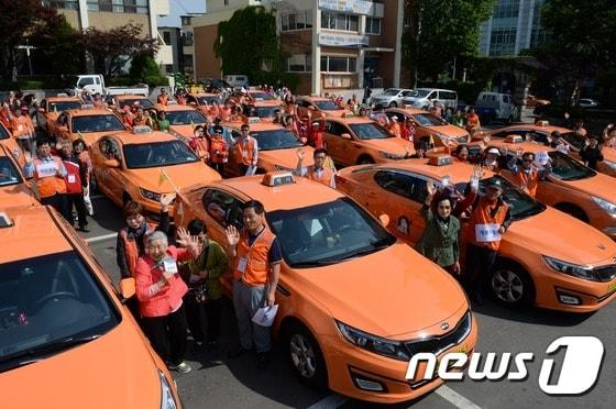 본문 이미지 - 해치택시 운전사들로 구성된 구로구 나들이 봉사단이 5월 13일 오전 서울 구로구청 마당에서 지역 저소득층 노인, 장애인과 함께 인천 강화도로 나들이 봉사활동을 떠나기 앞서 배웅객들에게 손을 흔들고 있다. 2015.5.13 ⓒ News1 정회성 기자