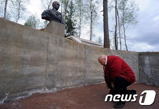 본문 이미지 - 러시아 준군사조직 코사크 민병대의 한 대원이 지난 16일(현지시간) 상트페테르부르크 외곽 아갈라토보에 세워진 로마제국 스타일의 블라디미르 푸틴 대통령 흉상에 무릎을 꿇고 경의를 표하고 있다. ⓒ AFP=뉴스1