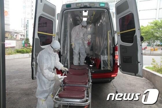본문 이미지 - 서울 중구소방서 119 구급대원이 메르스 의심 환자 이송 후 전신 보호복과 마스크를 착용하고 구급차량을 소독하고 있다(서울소방재난본부 제공)/뉴스1 ⓒ News1 조희연 기자