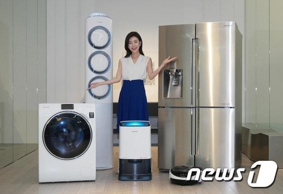 본문 이미지 - 삼성전자 모델이 18일 삼성전자 수원사업장 생활가전동 프리미엄 하우스에서 &acute;인버터 컴프레서&acute;와 &acute;인버터 모터&acute;의 무상보증 기간이 10년으로 일원화된 삼성 생활가전 제품들을 소개하고 있다. (왼쪽부터 시계방향으로 WW900 세탁기, 스마트에어컨 Q9000, 셰프컬렉션 냉장고, 파워봇 로봇청소기, 2015년형 인버터제습기)ⓒ News1
