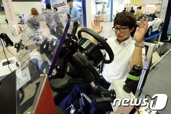 본문 이미지 - 지난 6월 24일 서울 강남구 삼성동 코엑스에서 열린 2015 국토교통기술대전을 찾은 관람객이 교통안전공단 자동차안전연구원의 자율주행자동차 시스템을 체험하고 있다. ⓒ News1