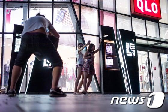 본문 이미지 - 15일 중국 베이징 소재 한 유니클로 매장 앞에서 젊은이들이 사진을 찍고 있다. 이 매장의 탈의실에서 찍은 것으로 추정되는 동영상이 SNS로 확산되면서 당국이 유포자 추적에 나섰다. ⓒ AFP=News1