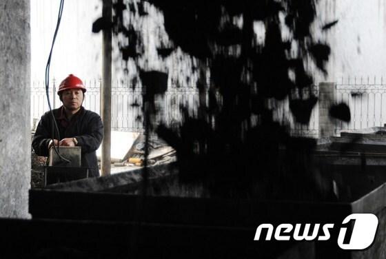 본문 이미지 - 한 중국 광부가 석탄을 수레에 싣고 있다.ⓒ AFP=뉴스1