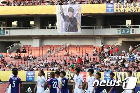 본문 이미지 - 김정은 북한 국방위원회 제1위원장의 대형 사진 현수막이 1일 오후 중국 후베이성 우한 스포츠센터에서 열린 2015 동아시아축구연맹(EAFF) 동아시안컵 여자 축구 대회 개막전 북한과 일본의 경기에서 북한 응원석 앞에 걸려 있다.2015.8.1/뉴스1 ⓒ News1 이광호 기자