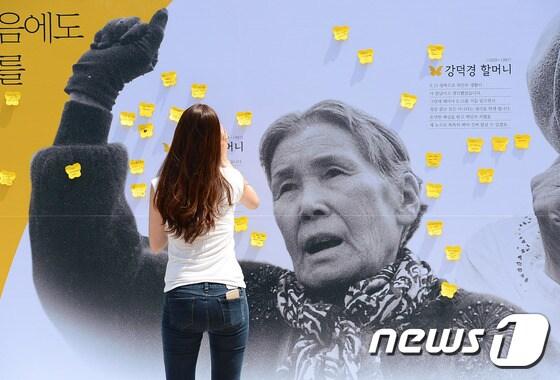 본문 이미지 - 시청 앞 서울광장에 설치된 위안부 할머니 사진과 생전 남긴 말을 담은 '아트월'에 시민들이 응원의 메시지를 붙이고 있다. 아트월에는 최초로 위안부 증언을 한 김학순 할머니와 일본정부의 사과를 촉구하는 운동을 벌이다 세상을 떠난 황금주, 강덕경 할머니의 얼굴 사진이 걸려있다. 2015.8.12/뉴스1 ⓒ News1 박세연 기자