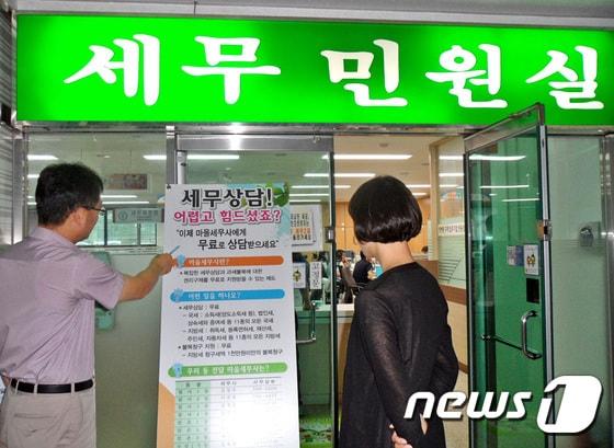 본문 이미지 - 대구 수성구 주민들이 지난 21일 수성구청 민원실 앞에 세워진  마을세무사 제도 홍보 배너를 바라보고 있다./사진제공=대구 수성구청 ⓒ News1