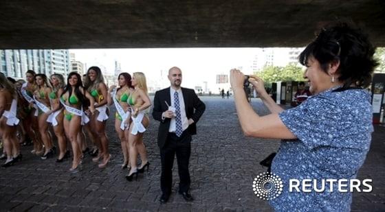본문 이미지 - A woman takes a photo of her friend with candidates of the Miss Bumbum Brazil 2015 pageant in Sao Paulo