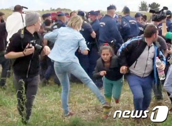 본문 이미지 - 헝가리 카메라기자가 아이를 안고 달리는 남성 난민에게 발을 걸어 넘어트린 영상이 공개된 가운데 이번에는 난민인 여자 어린이와 남자 어린이를 차례로 발로 찬 영상이 공개됐다. ⓒ AFP=뉴스1