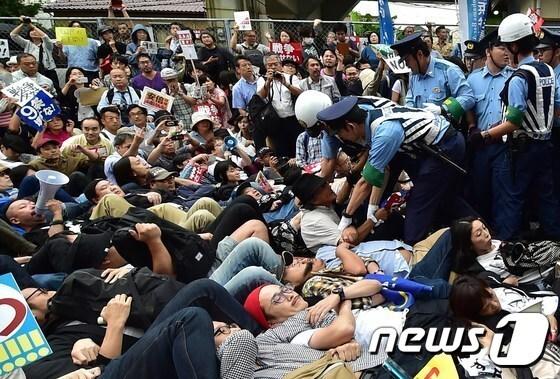 본문 이미지 - 지난 9월 안보법안을 반대하는 일본 시민들이 도쿄 의회 앞 도로에 누워 시위를 벌이고 있다. ⓒ AFP=News1