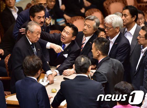 본문 이미지 - 고노이케 요시타다(鴻池祥肇) 참의원 평화안전법제 특별위원회 위원장(자민, 좌측)이 17일 오전 안보법안을 비판하는 야당 의원들에 둘러싸여 있다. ⓒ AFP=News1