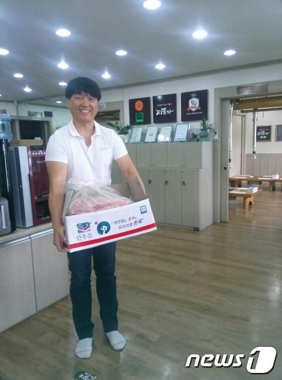 본문 이미지 - 24일 예산읍 주교리 지돈가에서 사회복지시설 관계자가 돼지고기를 전달받고 있다.ⓒ News1