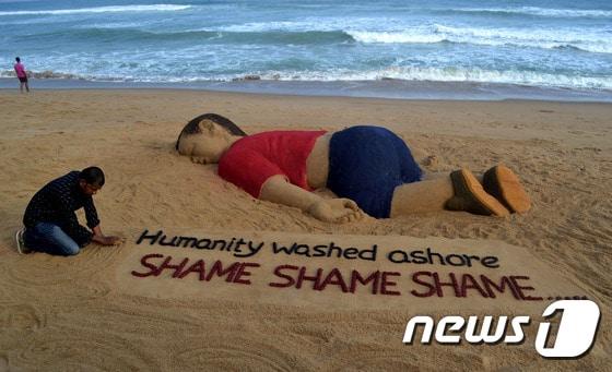 본문 이미지 - 인도 예술가인 수라드산 파트나익이 4일(현지시간) 인도 부바네스와르 인근 푸리 해안에 세 살배기 난민 아일란 쿠르디를 기리는 모래 조형물을 만들었다.  ⓒ AFP=뉴스1