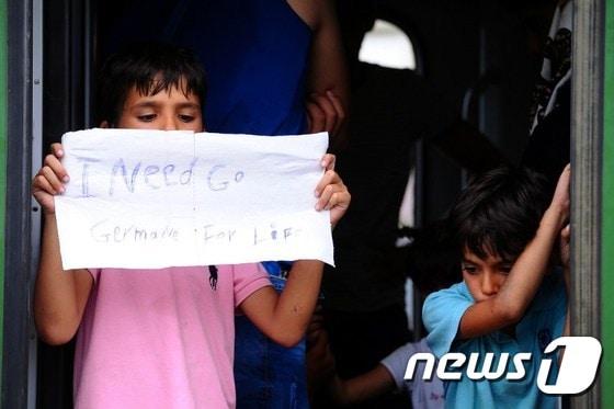 본문 이미지 - 지난 3일(현지시간) 헝가리 부다페스트에 머물고 있던 한 소년 난민이 "살기 위해 독일로 가야 해요"라는 종이 팻말을 들고 있다. ⓒ AFP=뉴스1