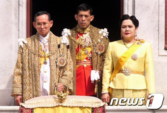 본문 이미지 - 13일(현지시간) 서거한 푸미폰 아둔야뎃 태국 국왕(왼쪽)과 시리킷 키티야카라 왕비(오른쪽), 아들인 마하 와찌랄롱꼰(64) 왕세자가 함께 서 있다. 사진은 1999년 12월 촬영됐다. ⓒ AFP=뉴스1
