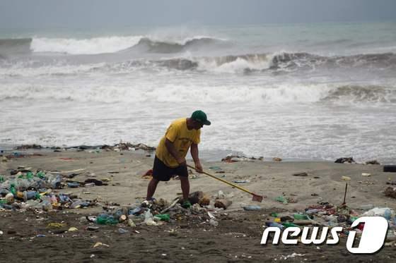 본문 이미지 - 허리케인 '매튜'의 영향으로 쓰레기가 밀려온 도미니카 공화국 산토도밍고의 해안가에서 주민들이 청소를 하고 있다. ⓒ AFP=뉴스1
