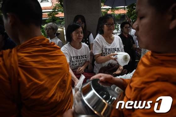 본문 이미지 - 6일(현지시간) 태국 방콕에서 열린 탐마삿대 학살 40주년 기념식에서 여성들이 탁발을 하고 있다. ⓒ AFP=뉴스1