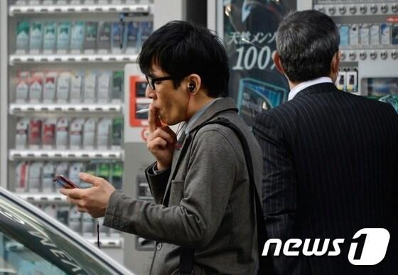본문 이미지 - 일본의 담배 자동판매기 앞에서 한 남성이 흡연 중이다.(자료사진) ⓒ AFP=뉴스1