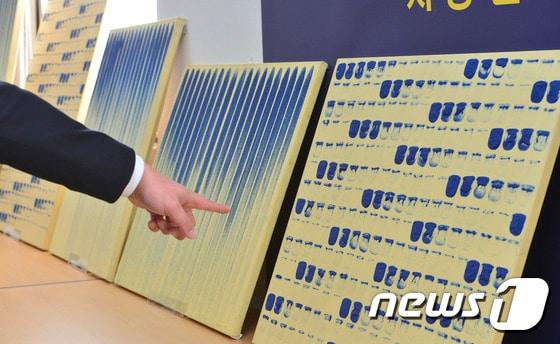 본문 이미지 - 15일 오전 서울 중랑구 서울지방경찰청 지능범죄수사대에서 경찰이 위조화가가 만들어낸 이우환 화백의 위작을 살펴보고 있다. 지능범죄수사대는 이날 이 화백의 그림 '점으로부터'와 '선으로부터' 등 약 40점을 위조한 혐의로 위조화가 박모씨(56) 등 6명을 구속했다고 밝혔다. 2016.11.15/뉴스1 ⓒ News1 신웅수 기자