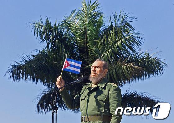 본문 이미지 - 2001년 1월 27일 쿠바 수도 아바나 인근 도시 산호세데라스라하스를 방문한 피델 카스트로 당시 국가평의회 의장이 국기를 들고 있다. 쿠바 공산혁명 지도자 카스트로 전 의장은 26일 타계했다. ⓒ AFP=뉴스1 ⓒ News1 최종일 기자