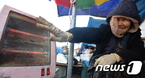 본문 이미지 - 11일 대전·충남에선 대부분의 지역에 아침 기온이 5도 이하로 내려가 추울 것으로 예보됐다. 대전 동구 중앙시장에서 한 상인이 전기히터를 켜 놓고 몸을 녹이고 있다. /뉴스1 ⓒ News1