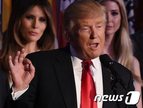 본문 이미지 - 미국의 제45대 대통령으로 당선된 도널드 트럼프 공화당 후보가 9일(현지시간) 뉴욕 힐튼 미드타운에서 당선 소감을 전하며 특유의 제스처를 취했다. 뒤로 부인인 멜라니아(왼쪽)와 이반카의 얼굴이 보인다. ⓒ AFP=뉴스1