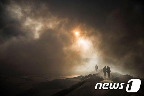 본문 이미지 - 이슬람국가(IS)가 이라크 모술 인근에 저지른 대규모 유전 화재가 지속되면서 지난달 20일(현지시간) 알콰야라 마을에 독성 가스가 피어오르고 있다. ⓒ AFP=뉴스1
