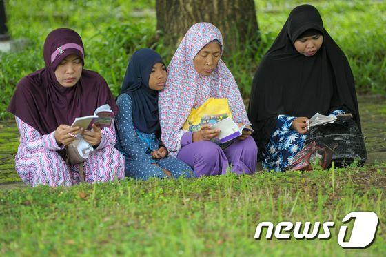 본문 이미지 - 26일(현지시간) 인도네시아 아체주에 있는 공동 묘지에서 가족들이 기도하고 있다. ⓒ AFP=뉴스1