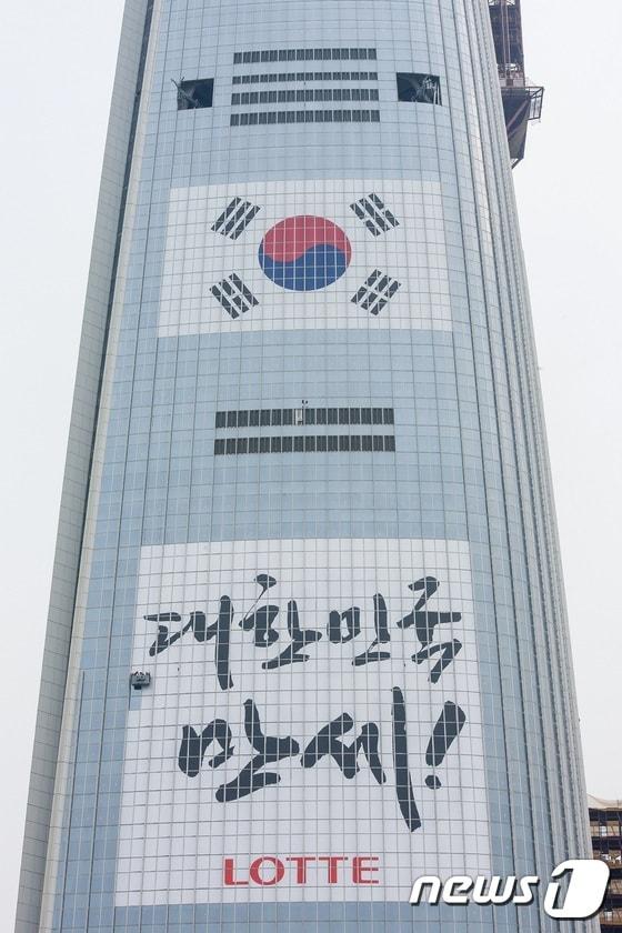본문 이미지 - 롯데월드타워가 삼일절을 기념해 '대한민국 만세!' 메시지를 건물 외벽에 부착하는 작업을 진행하고 있다. ⓒ News1